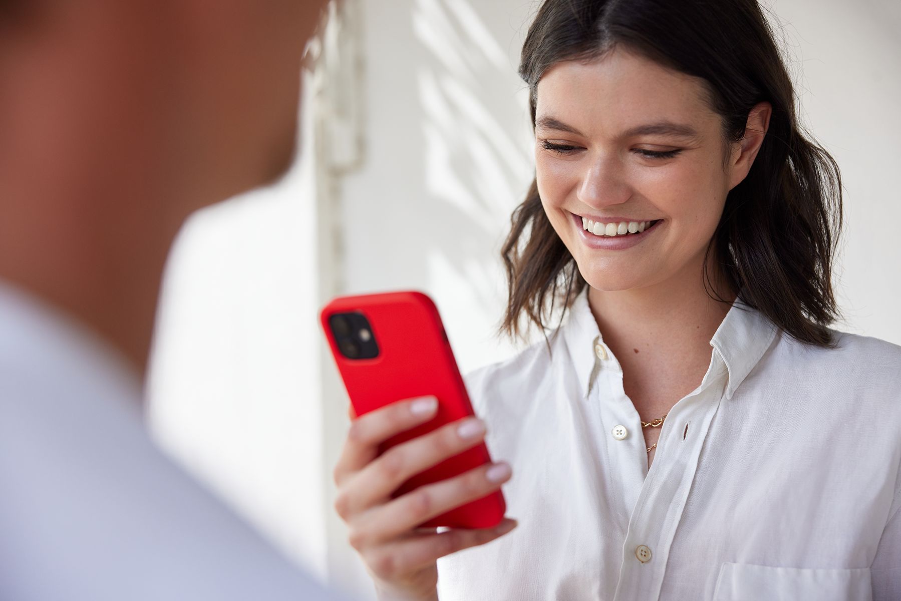Uśmiechnięta kobieta sprawdza aplikację mobilną DPD Polska na smartfonie w biurze